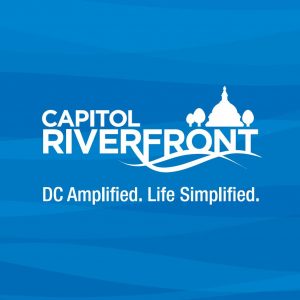 White Capitol Riverfront logo on a blue background with a silhouette of the U.S. Capitol dome and trees. Below, it reads "DC Amplified. Life Simplified." in white text.