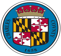 A round seal featuring a crowned shield divided into Maryland state flag quarters, with "CHARLES COUNTY 1658" in black letters on a blue border around the shield.