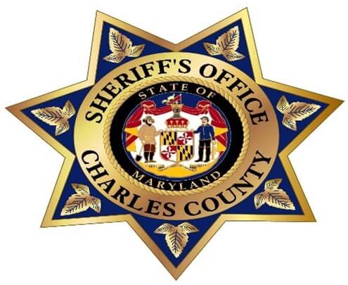 A gold and blue seven-pointed sheriff's badge with "Sheriff's Office Charles County" written around the Maryland state seal in the center.