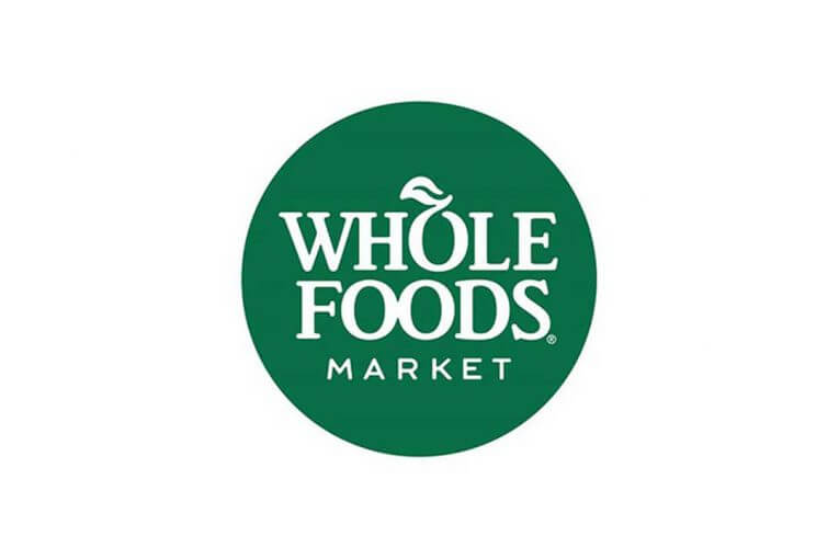 The Whole Foods Market logo features the brand name in white capital letters inside a green circle, with a small leaf incorporated into the letter "O" in "WHOLE.